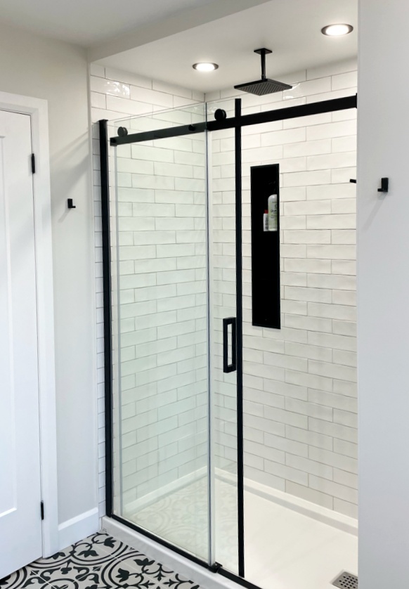 Walk-in shower with white subway tile and black-framed glass door in a renovated Ottawa bathroom