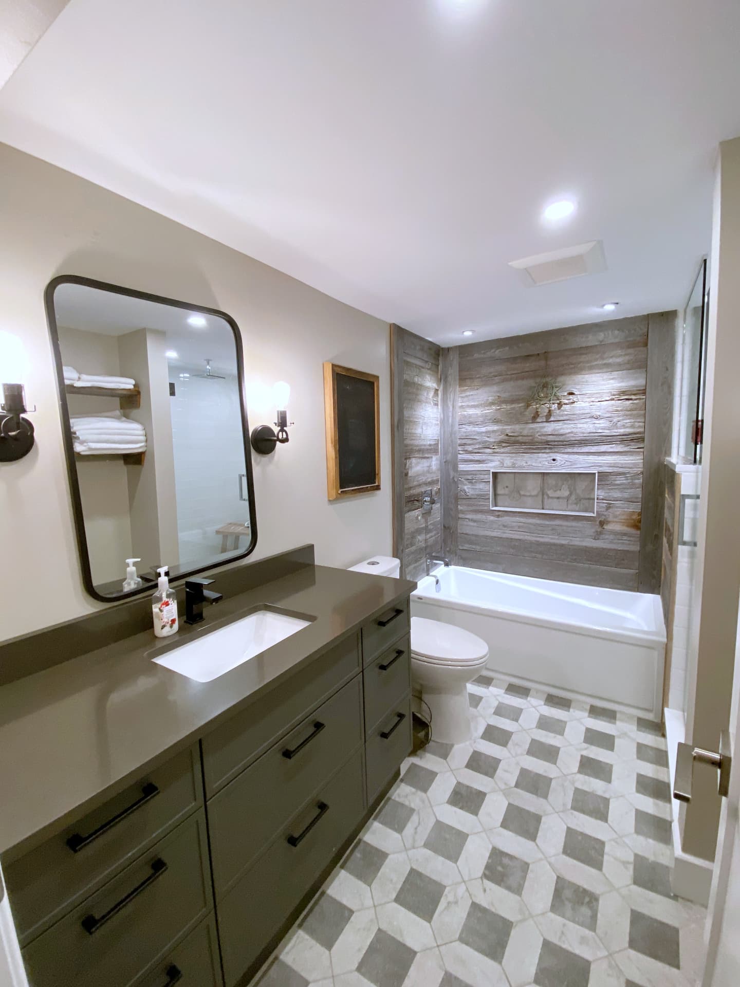 Olive-green bath vanity with grey quartz top, black hardware and framed mirror