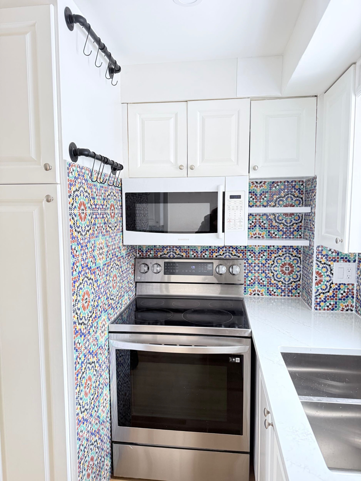 Galley kitchen range wall clad in colourful Moroccan mosaic tile beneath white cabinetry