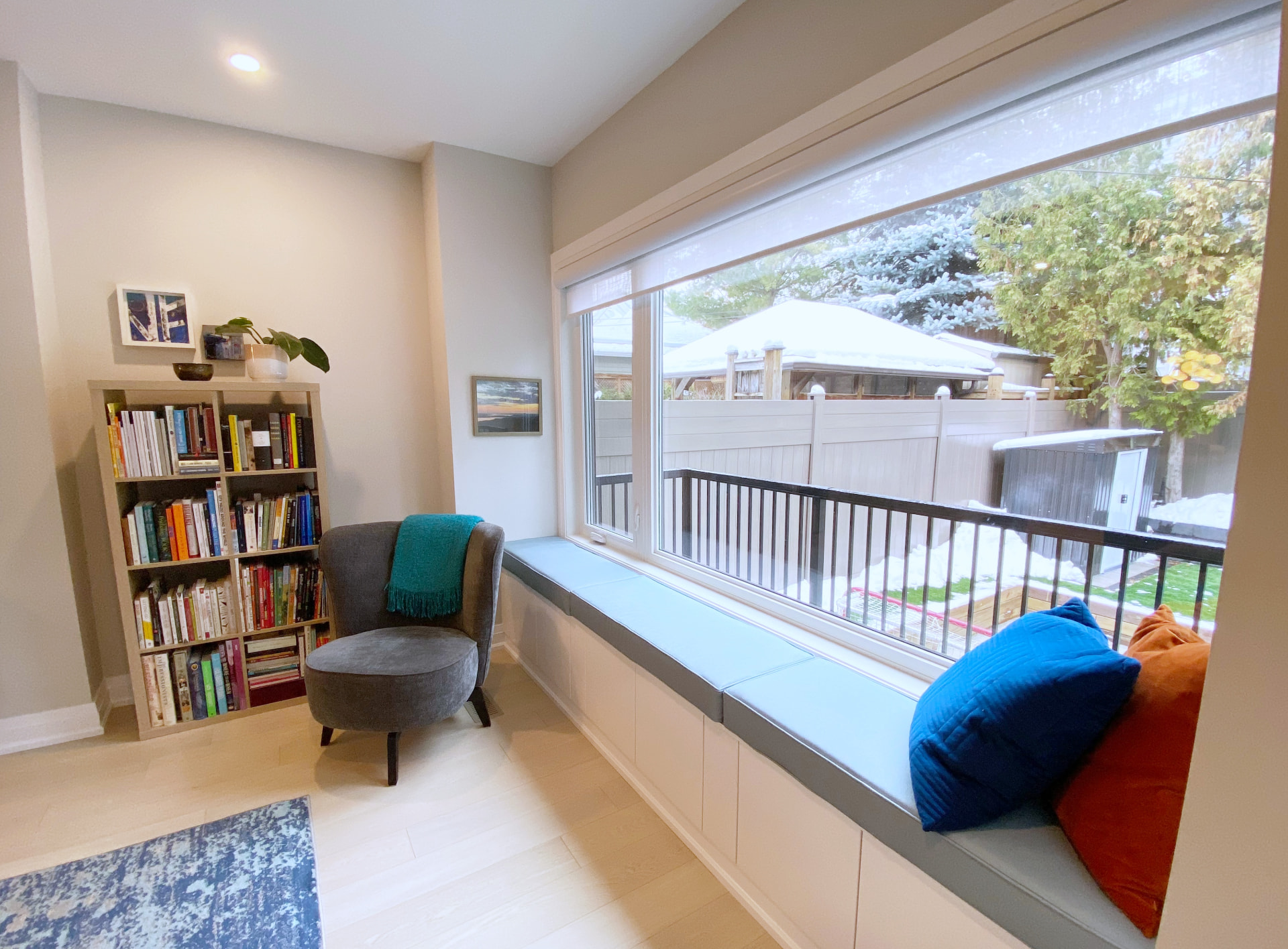 Built-in window seat with storage drawers beneath a wide picture window and a bookcase
