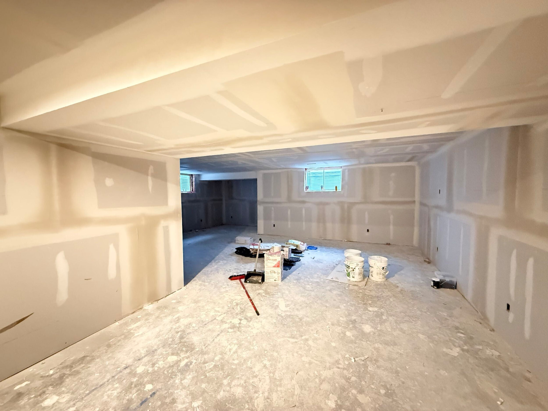 Framed and drywalled basement showing the open living area and window wells