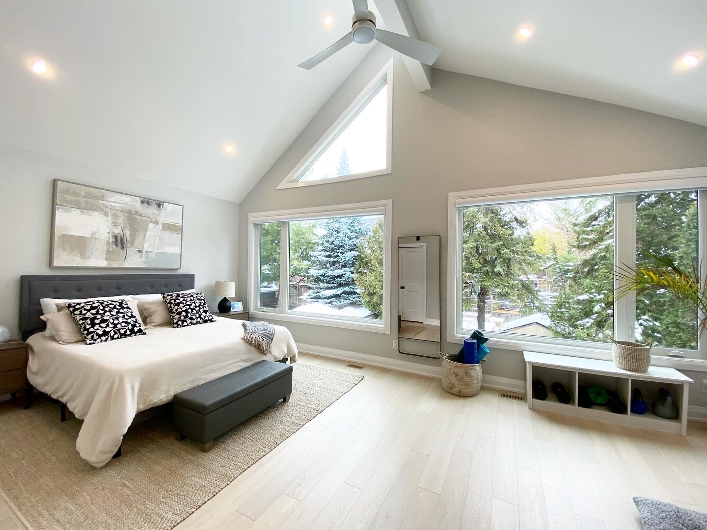 Vaulted primary bedroom with exposed ridge beam, triangular gable window and pale oak floors