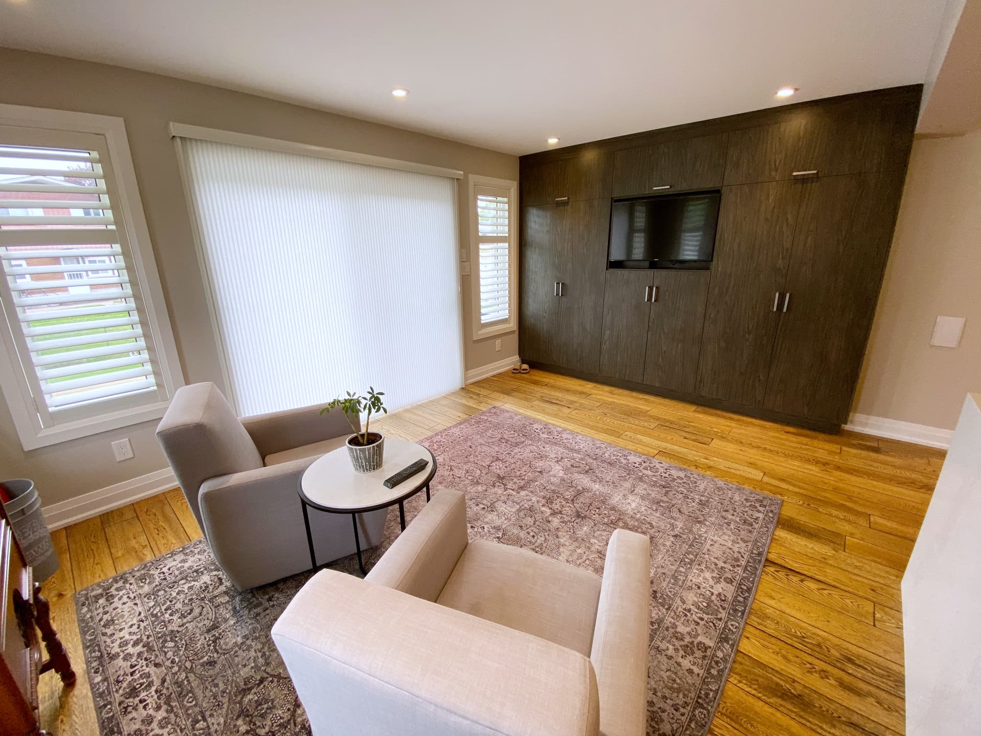 Front sitting room with a floor-to-ceiling smoked oak millwork wall concealing storage and a television
