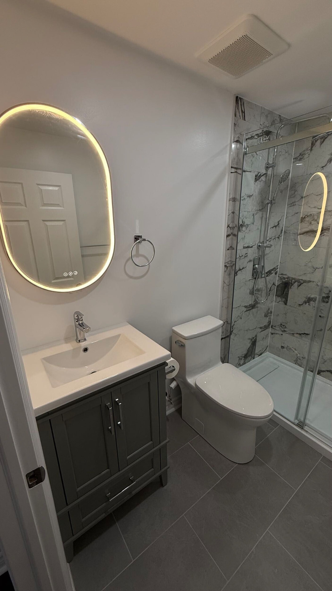 Deep green shaker vanity with white ceramic top and a backlit oval LED mirror