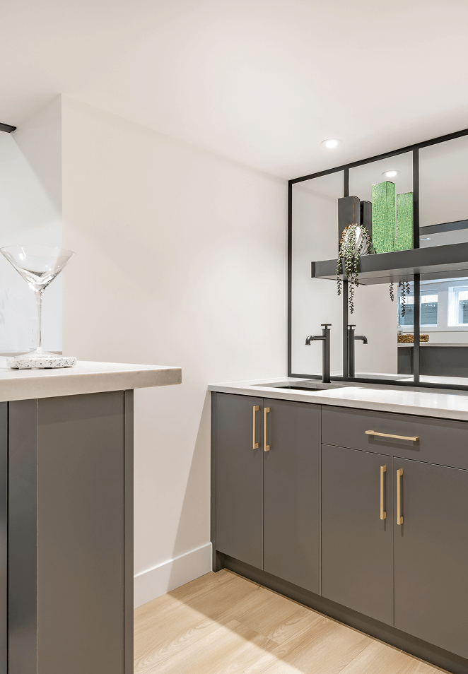 Grey basement wet bar with gold handles and mirrored splashback