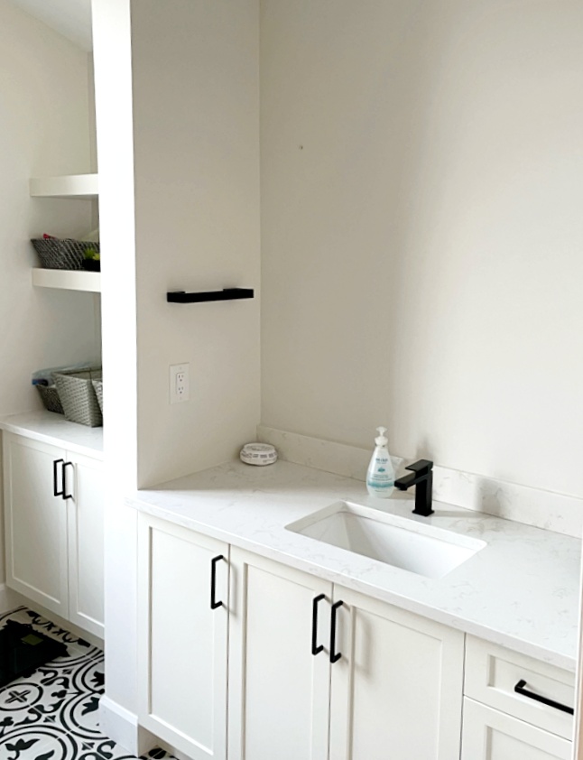 White shaker vanity cabinetry with black handles and grey patterned floor in a renovated Ottawa bathroom