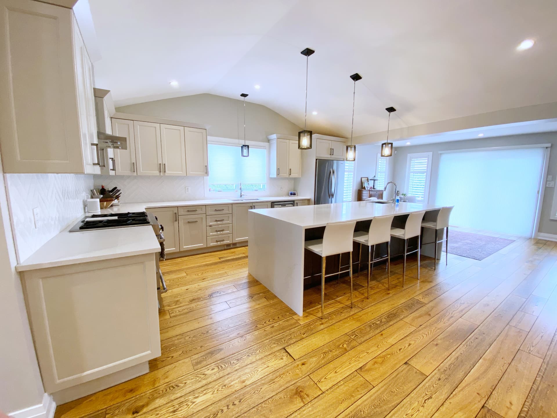 Wide view of the finished vaulted kitchen with a long quartz island and white cabinetry