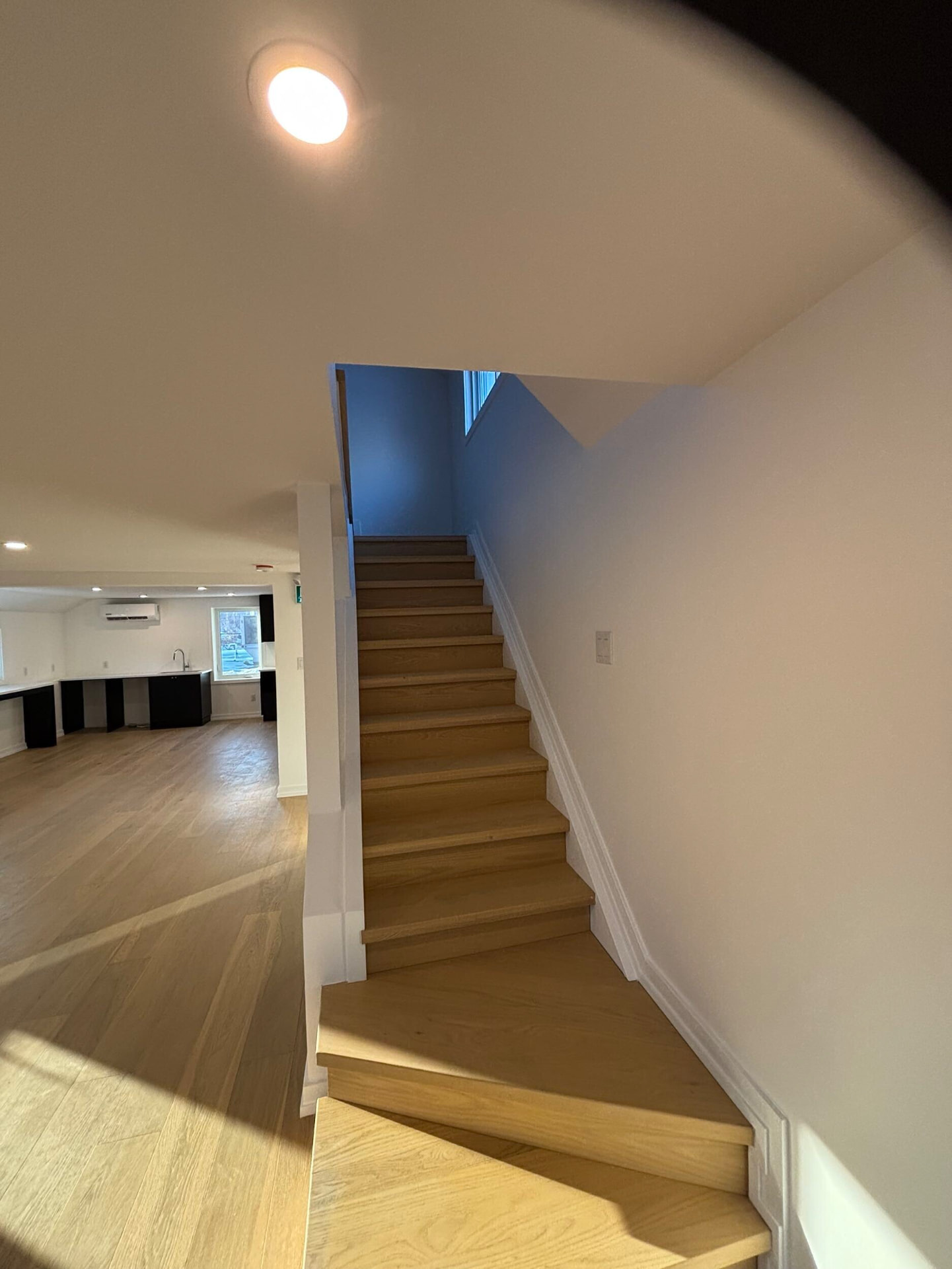 White oak staircase with clean white walls and recessed lighting