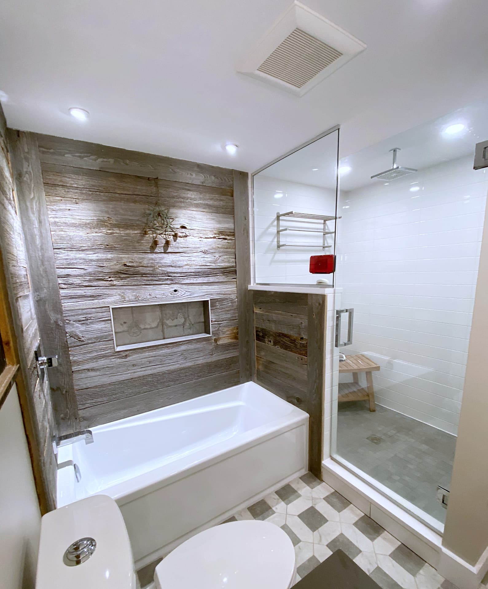 Barnwood-clad tub wall next to a white-tiled glass shower with a rain head