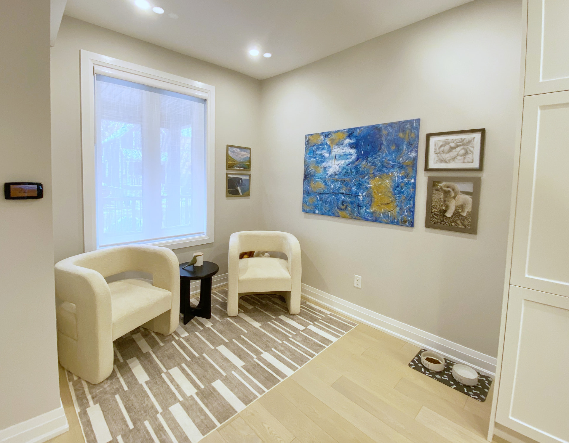 Small sitting nook with two boucle chairs, a side table and framed art