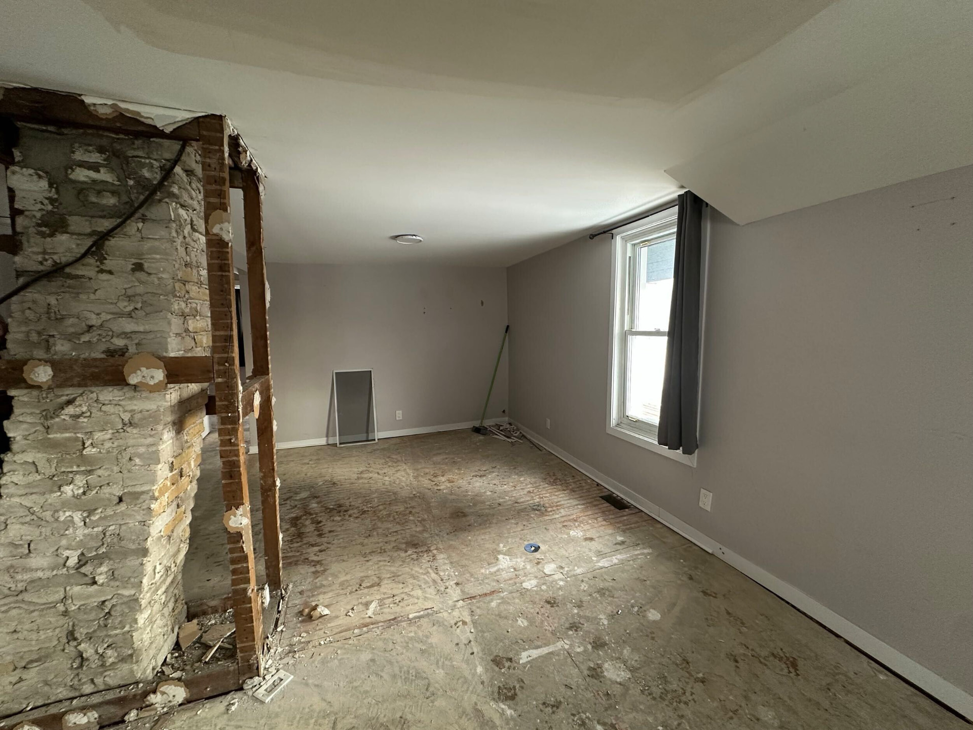 Stripped interior showing exposed stone wall, framing and subfloor during demolition