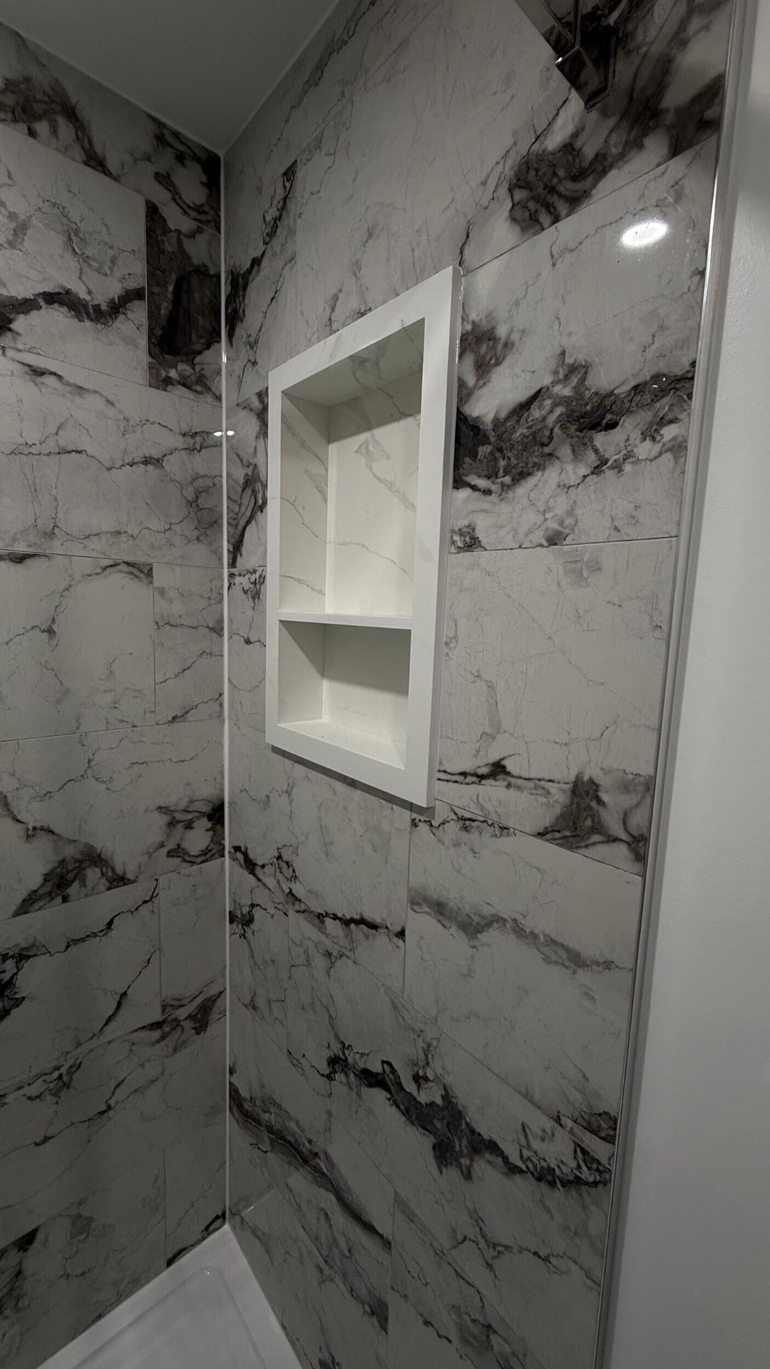 Two-tier recessed shower niche trimmed in mitred marble-look porcelain tile