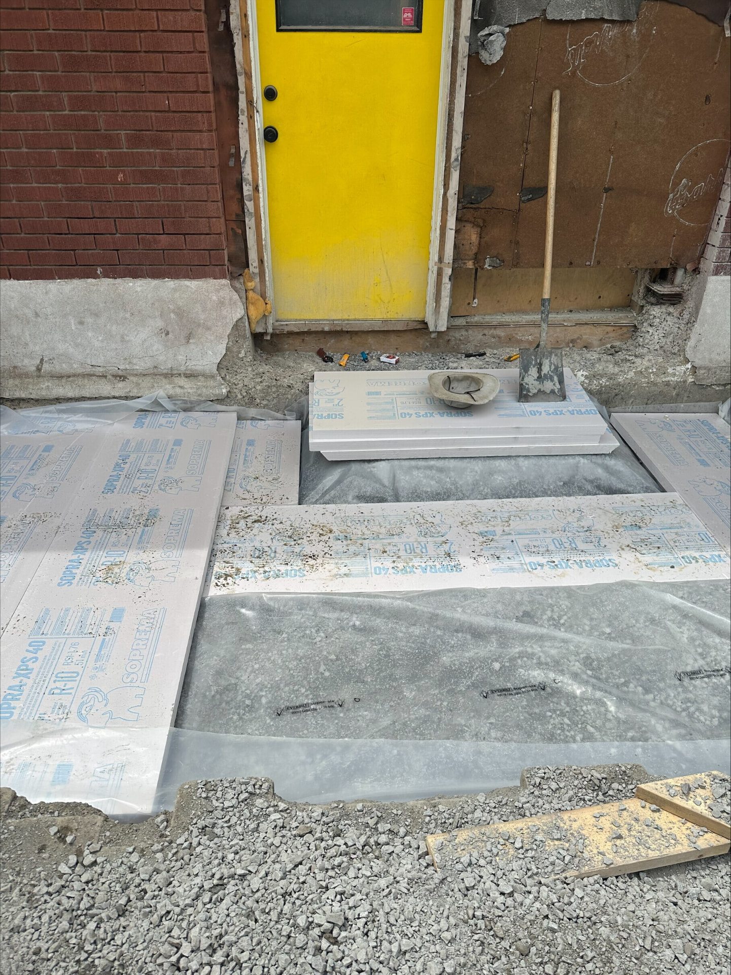 Rigid XPS insulation boards and poly vapour barrier laid over compacted gravel before a slab pour