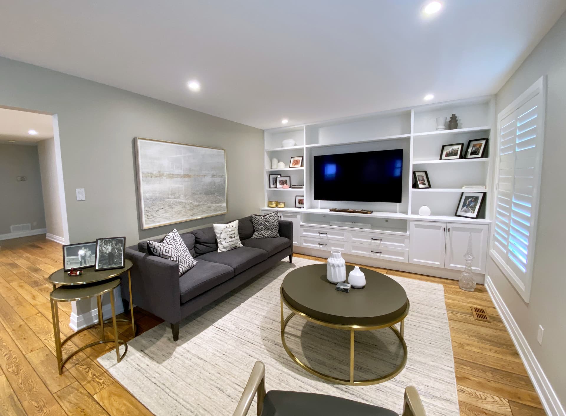 Finished family room with full-height white built-in cabinetry around a wall-mounted television