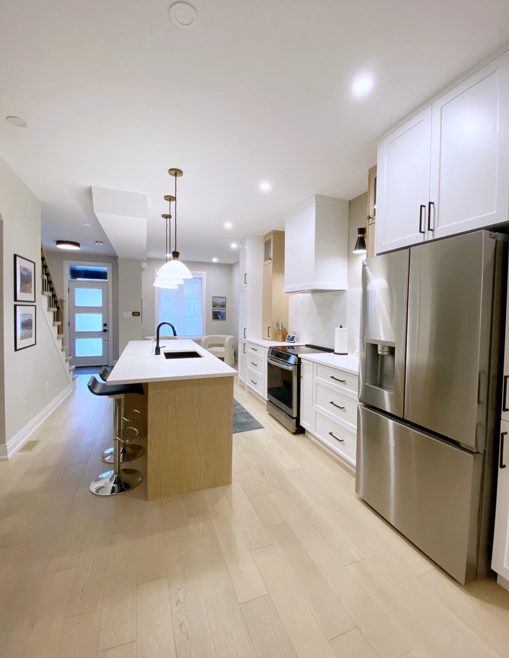 View from the entry along the kitchen with white oak island and bar stools
