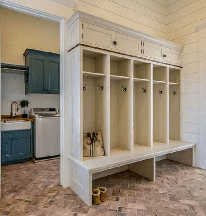 White mudroom with cubbies and a wooden bench during a home renovation