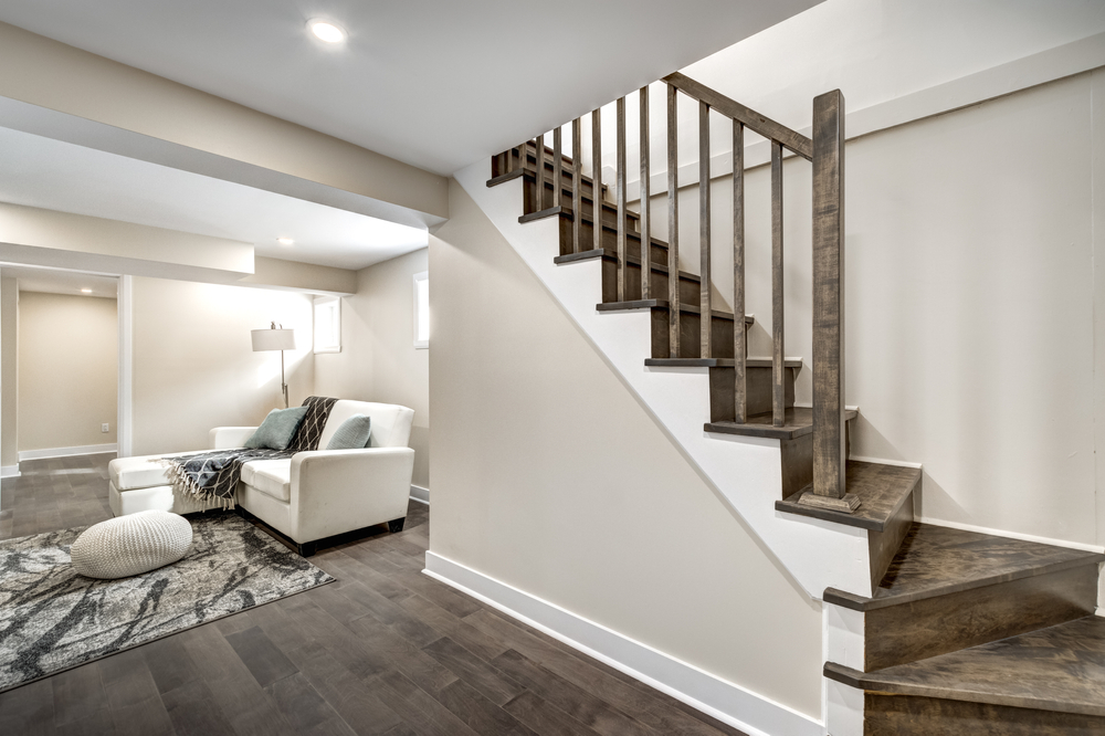Renovated basement and stairs with dark floors, a new white couch, and cozy carpet